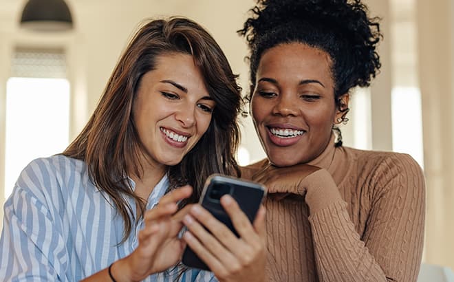 Two women looking at the same mobile